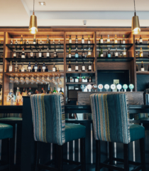 The image features a modern hotel lobby with shiny marble floors, plush seating, decorative plants, and ambient lighting, creating a welcoming and luxurious atmosphere.